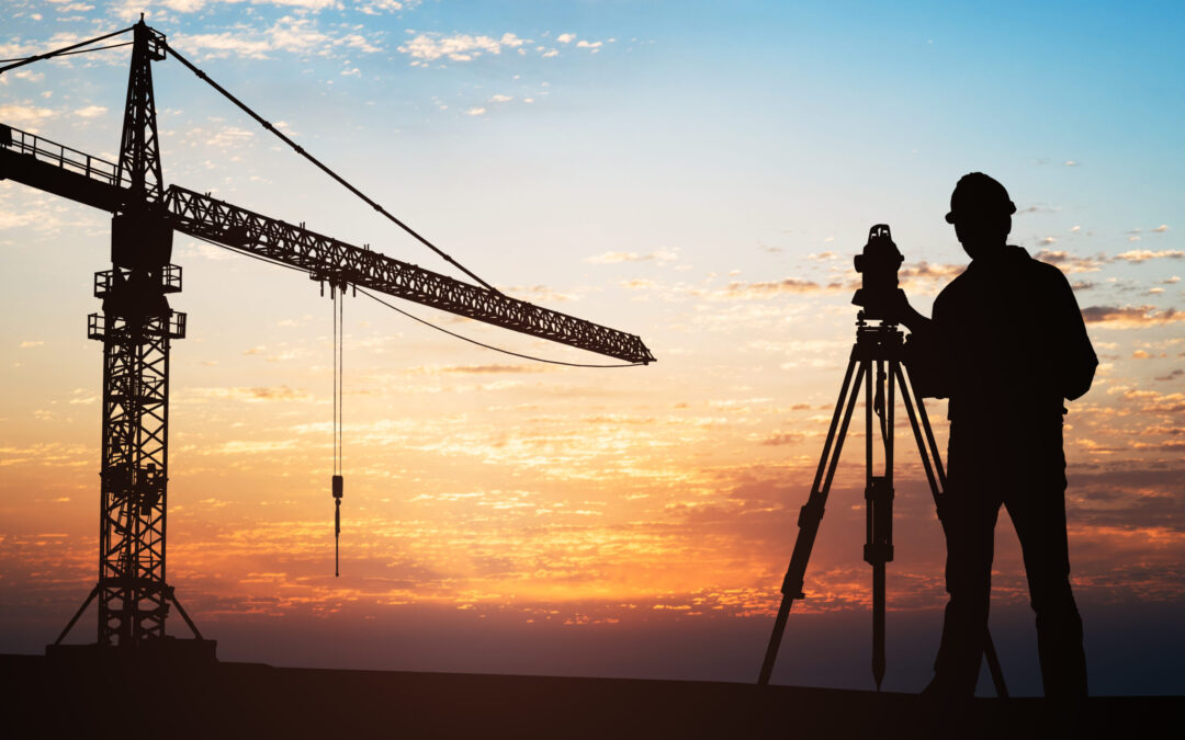 Surveyor Standing Near Crane At Construction Site